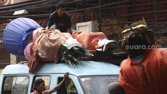 Warga menaikkan ondel-ondel ke atas mobil angkutan umum di Kampung Ondel-ondel, Jalan Kembang Pacar, Senen, Jakarta, Rabu (12/8/2020). [Suara.com/Angga Budhiyanto]