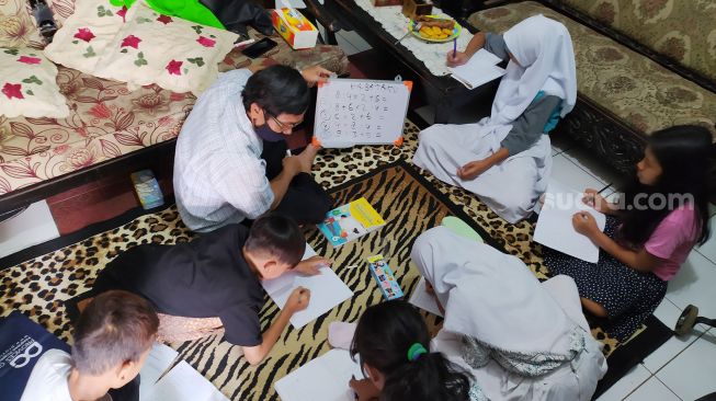 Guru dan siswa melakukan kegiatan belajar mengajar di rumah siswa di Menteng, Jakarta, kamis (13/8).[Suara.com/Oke Atmaja]