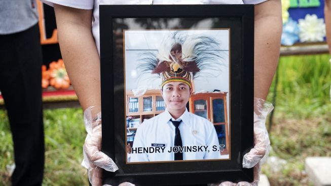 Petugas membawa foto anggota KPU Yakuhimo, Papua almarhum Hendry Jovinski saat proses pemakaman di Rewulu Wetan, Sidokarto, Godean, Sleman, Yogyakarta, Kamis (13/8/2020).  [ANTARA FOTO/Andreas Fitri Atmoko]