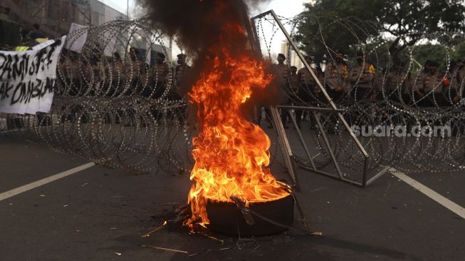 Massa mahasiswa dari berbagai universitas membakar ban saat melakukan aksi unjuk rasa di sekitar Gedung DPR/MPR RI, Jumat (14/8/2020). [Suara.com/Angga Budhiyanto]