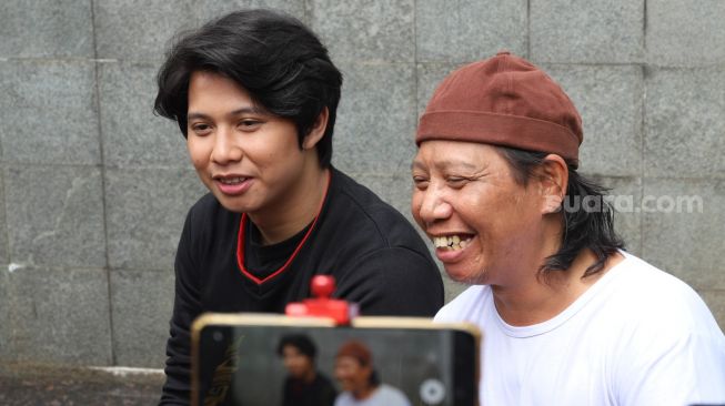 Ekspresi Komedian Mastur dan putranya Ahmad Syaiful saat menjawab pertanyaan awak media di Kawasan Tendean, Jakarta Selatan, Jumat (14/8). [Suara.com/Alfian Winanto]