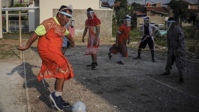 Peserta menggunakan pelindung muka saat mengikuti perlombaan sepak bola pria dengan kostum wanita di Cinunuk, Kabupaten Bandung, Jawa Barat, Sabtu (15/8/2020). [ANTARA FOTO/Raisan Al Farisi]