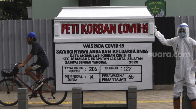 Pesepeda melintas di dekat seni instalasi tenaga medis yang sedang memegang peti jenazah korban COVID-19 di simpang jalan Kemang 1, Jakarta Selatan, Minggu (16/8/2020). [Suara.com/Angga Budhiyanto]