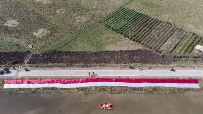 Foto udara kain Merah Putih dibentangkan oleh komunitas Pasukan Susur Sungai dan Ekosistem Rancaekek (Passer) di sungai Cikijing, Rancaekek, Kabupaten Bandung, Jawa Barat, Minggu (16/8/2020). [ANTARA FOTO/M Agung Rajasa]