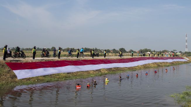 Komunitas Pasukan Susur Sungai dan Ekosistem Rancaekek (Passer) membentangkan kain Merah Putih di bantaran sungai Cikijing, Rancaekek, Kabupaten Bandung, Jawa Barat, Minggu (16/8/2020). [ANTARA FOTO/M Agung Rajasa]