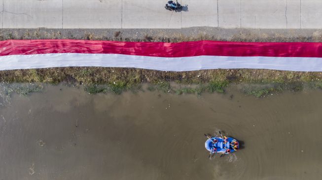 Foto udara kain Merah Putih dibentangkan oleh komunitas Pasukan Susur Sungai dan Ekosistem Rancaekek (Passer) di sungai Cikijing, Rancaekek, Kabupaten Bandung, Jawa Barat, Minggu (16/8/2020). [ANTARA FOTO/M Agung Rajasa]