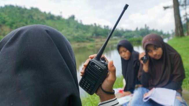 Siswa MTS Pakis belajar menggunakan Handy Talkie (HT) di tepian Telaga Kumpe, Desa Gununglurah, Kecamatan Cilongok, Kabupaten Banyumas, Sabtu (15/8/2020). [Suara.com/Anang Firmansyah]