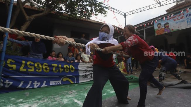 Peserta mengikuti perlombaan tarik tambang untuk memeriahkan Hari Kemerdekaan Republik Indonesia di kawasan Cinangka, Depok, Jawa Barat, Minggu (17/8/2020). [Suara.com/Angga Budhiyanto]