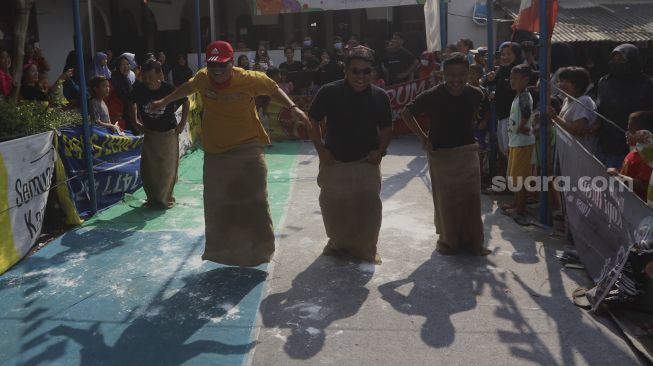 Peserta mengikuti perlombaan balap karung untuk memeriahkan Hari Kemerdekaan Republik Indonesia di kawasan Cinangka, Depok, Jawa Barat, Minggu (17/8/2020). [Suara.com/Angga Budhiyanto]