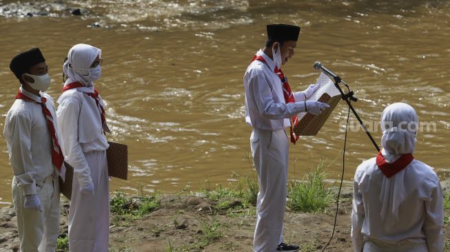 Petugas upacara membcakan naskah UUD 45 saat melaksanakan upacara bendera di Sungai Ciliwung, GDC, Depok, Jawa Barat, Senin (17/8/2020). [Suara.com/Angga Budhiyanto]