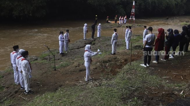 Petugas saat melaksanakan upacara bendera di Sungai Ciliwung, GDC, Depok, Jawa Barat, Senin (17/8/2020). [Suara.com/Angga Budhiyanto]