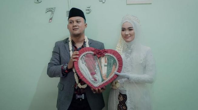 Pasangan pengantin, Muhammad Arif Al Fajar dan Tsaniyah usai menjalani akad nikah memperlihatkan bendera merah putih sebagai mahar mas kawin. (Sabtu, 15/8/2020) [Foto: Istimewa]