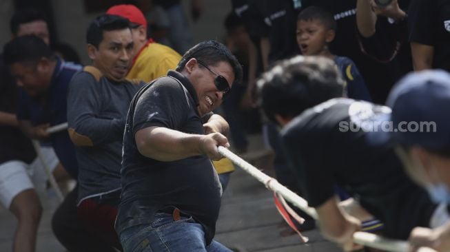 Peserta mengikuti perlombaan tarik tambang untuk memeriahkan Hari Kemerdekaan Republik Indonesia di kawasan Cinangka, Depok, Jawa Barat, Minggu (17/8/2020). [Suara.com/Angga Budhiyanto]