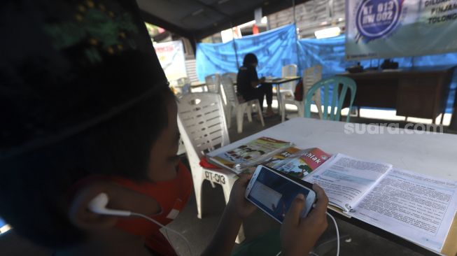 Sejumlah siswa belajar secara online di tenda wifi gratis di taman warga RT 013, Pondok Kelapa, Jakarta Timur, Selasa (18/8/2020). [Suara.com/Angga Budhiyanto]