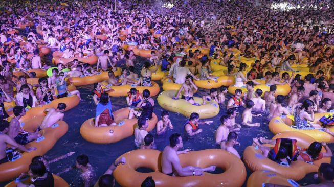 Foto yang diambil pada tanggal 15 Agustus 2020 menunjukkan orang-orang menonton pertunjukan saat mereka mendinginkan diri di sebuah kolam renang di Wuhan, Provinsi Hubei, China. [STR / AFP]