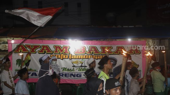 Sejumlah warga melakukan pawai obor di Kawasan Rempoa, Tangerang Selatan, Rabu (19/8/2020). [Suara.com/Angga Budhiyanto]