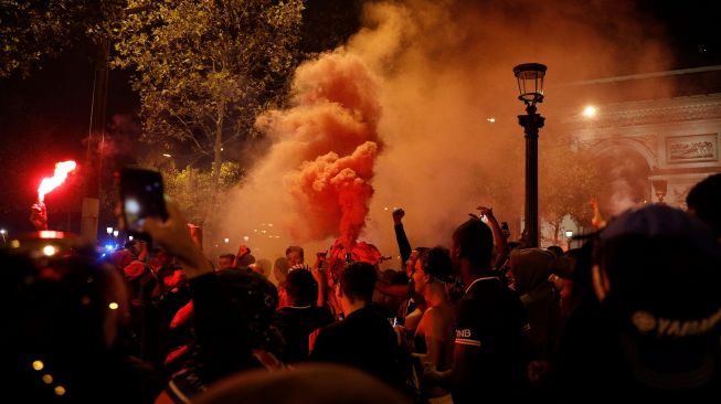 Suporter Paris Saint-Germain (PSG) merayakan kemenangan 3-0 tim mereka atas RB Leipzig yang membuat PSG lolos ke final Liga Champions di Champs-Elysees Avenue dekat Arc de Triomphe, Paris, Perancis, Rabu (19/8) dini hari WIB.  [GEOFFROY VAN DER HASSELT / AFP]