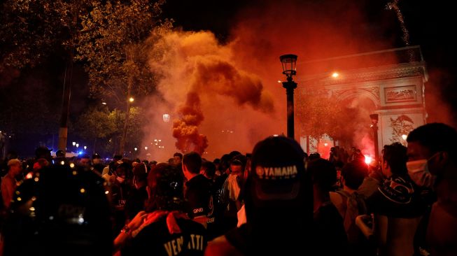 Suporter Paris Saint-Germain (PSG) merayakan kemenangan 3-0 tim mereka atas RB Leipzig yang membuat PSG lolos ke final Liga Champions di Champs-Elysees Avenue dekat Arc de Triomphe, Paris, Perancis, Rabu (19/8) dini hari WIB.  [GEOFFROY VAN DER HASSELT / AFP]