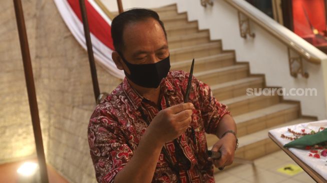 Petugas museum memindahkan pusaka berupa mata tombak saat melakukan ritual jamasan di Museum Pusaka Taman Mini Indonesia Indah (TMII), Jakarta, Kamis (20/8/2020). [Suara.com/Angga Budhiyanto]