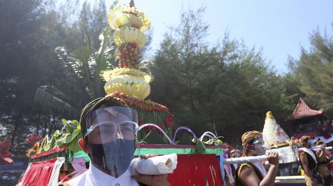 Warga memikul sesaji yang akan dilarung ke laut di Pantai Serang, Blitar, Jawa Timur, Jumat (21/8/2020). [ANTARA FOTO/Irfan Anshori]