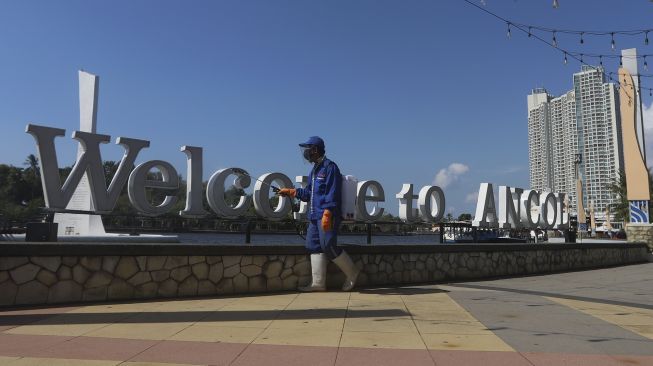 Seorang petugas menyemprotkan cairan disinfektan di kawasan pantai Ancol, Jakarta Utara, Jumat (21/8/2020). [Suara.com/Angga Budhiyanto]