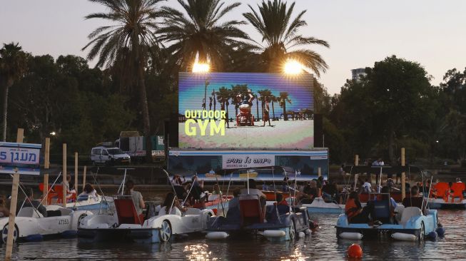 Sejumlah warga Israel menonton film sambil duduk di perahu pedal di bioskop terapung Sail-in di Taman Hayarkon Tel Aviv, Israel, (20/8/2020). [JACK GUEZ / AFP]