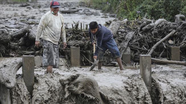 Warga membersihkan material lahar dingin di Desa Gurukinayan, Kabupaten Karo, Sumatera Utara, Sabtu (22/8/2020).  [ANTARA FOTO/Adiva Niki]