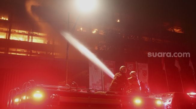 Petugas pemadam kebakaran berusaha memadamkan api yang membakar Gedung Kejaksaan Agung Republik Indonesia di Jakarta, Sabtu (22/8/2020). [Suara.com/Angga Budhiyanto]