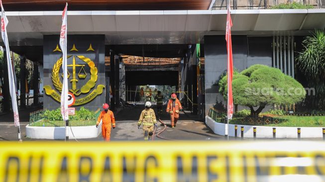 Petugas Damkar DKI berjalan keluar usai melakukan proses pendinginan di Gedung Utama Kejaksaan Agung RI di Jalan Sultan Hasanuddin, Jakarta Selatan, Minggu (23/8). [Suara.com/Alfian Winanto]