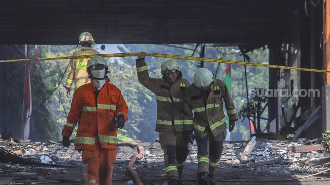 Petugas Damkar DKI berjalan keluar usai melakukan proses pendinginan di Gedung Utama Kejaksaan Agung RI di Jalan Sultan Hasanuddin, Jakarta Selatan, Minggu (23/8). [Suara.com/Alfian Winanto]