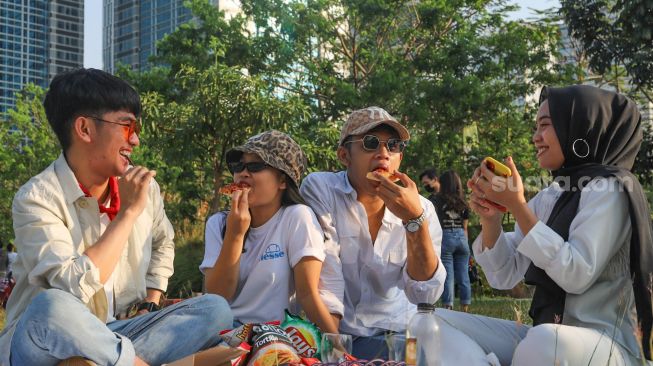 Warga piknik di area Hutan Kota Gelora Bung Karno, Senayan, Jakarta Sekatan, Minggu (23/8). [Suara.com/Alfian Winanto]