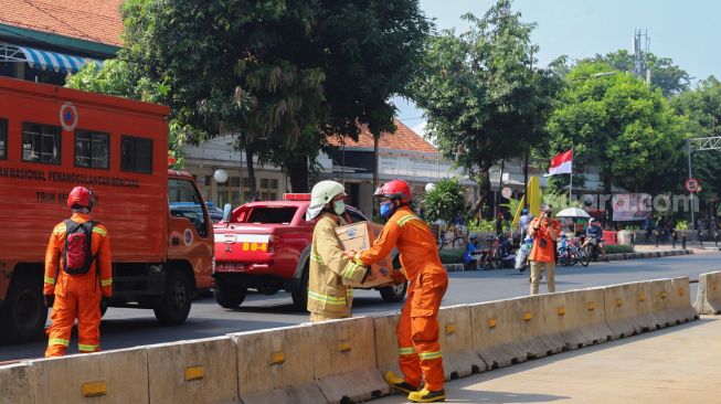 Petugas Damkar DKI mengambil suplai makanan usai melakukan proses pendinginan di Gedung Utama Kejaksaan Agung RI di Jalan Sultan Hasanuddin, Jakarta Selatan, Minggu (23/8). [Suara.com/Alfian Winanto]