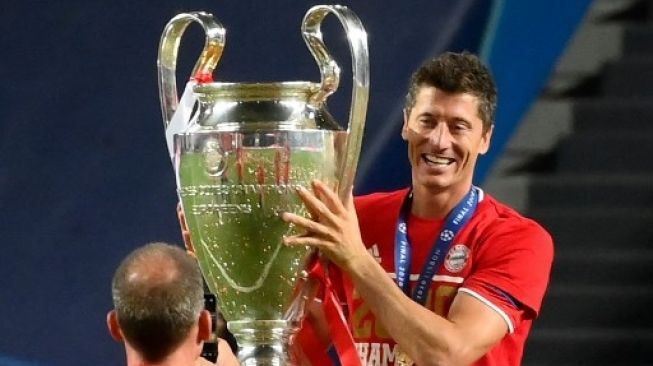 Striker Bayern Munich Robert Lewandowski mengangkat trofi LIga Champions setelah skuatnya mengalahkan Paris Saint-Germain pada laga final di Luz stadium. LLUIS GENE / POOL / AFP