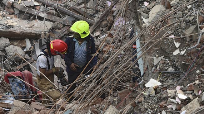 Petugas penyelamat mencari korban di reruntuhan gedung apartemen yang ambruk di Mahad, India, Selasa (25/8). [Punit PARANJPE / AFP]