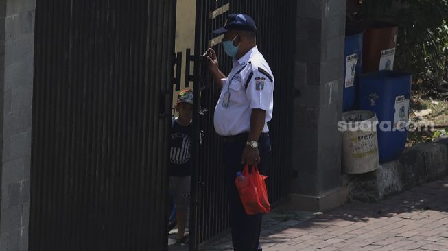 Petugas keamanan menerima makanan dari keluarga pasien di Gelanggang Olahraga Remaja (GOR) Tambora, Jakarta, Rabu (26/8/2020). [Suara.com/Angga Budhiyanto]