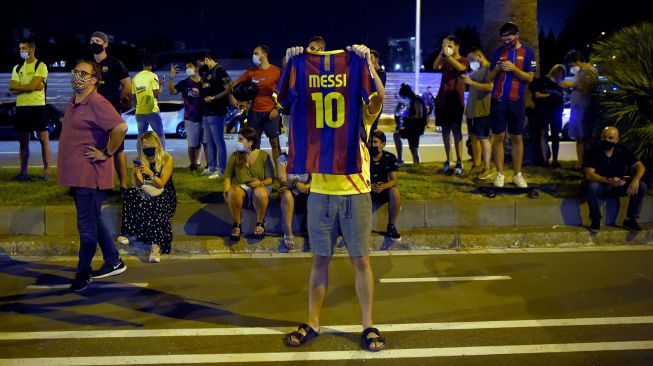 Fans Barcelona membentangkan jersey Barcelona beruliskan Messi saat menggelar aksi di luar markas klub, Barcelona, ​​Spanyol, Selasa (25/8). [Pau BARRENA / AFP]