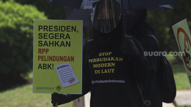 Aktivis buruh yang tergabung dalam Serikat Buruh Migran Indonesia (SBMI) dan Greenpeace Indonesia membawa poster saat melakukan aksi damai di depan Istana Merdeka, Jakarta, Kamis (27/8/2020). [Suara.com/Angga Budhiyanto]