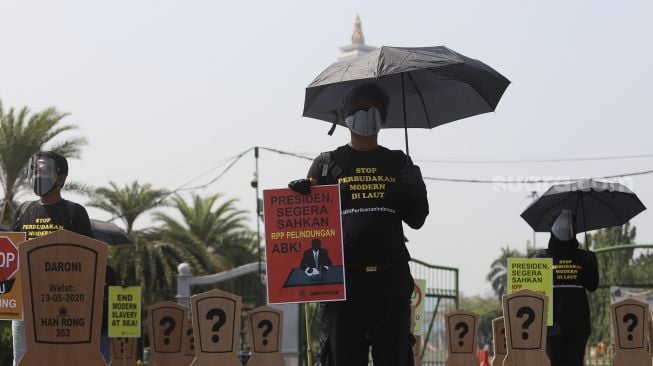 Aktivis buruh yang tergabung dalam Serikat Buruh Migran Indonesia (SBMI) dan Greenpeace Indonesia membawa poster saat melakukan aksi damai di depan Istana Merdeka, Jakarta, Kamis (27/8/2020). [Suara.com/Angga Budhiyanto]