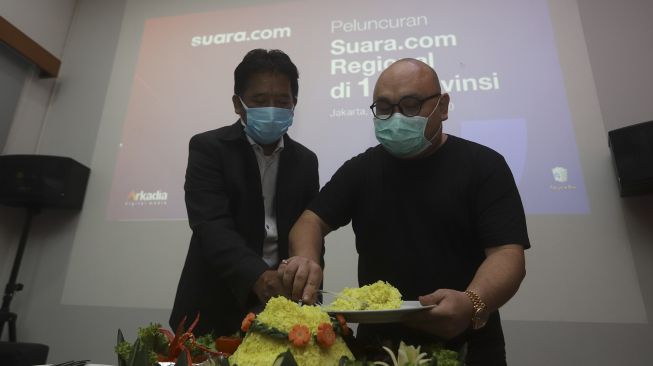 Direktur Utama PT Arkadia Digital Media Wiliam Martaputra (kanan) didampingi Pemimpin Redaksi Suara.com Suwarjono memotong tumpeng saat Peluncuran Suara.com Regional di 14 Provinsi di Kantor Redaksi Suara.com, Jakarta, Jumat (28/8/2020). [Suara.com/Angga Budhiyanto]