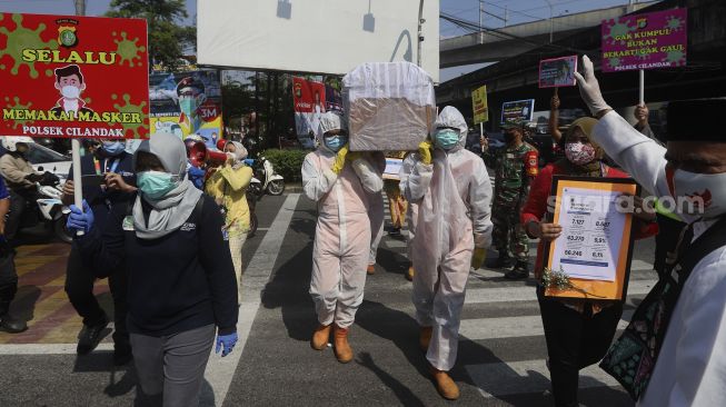 Petugas gabungan dari Kecamatan Cilandak dan Polsek Cilandak melakukan aksi sosialisasi bahaya COVID-19 dengan mengarak instalasi peti mati jenazah di kawasan Fatmawati, Jakarta, Jumat (28/8/2020). [Suara.com/Angga Budhiyanto]