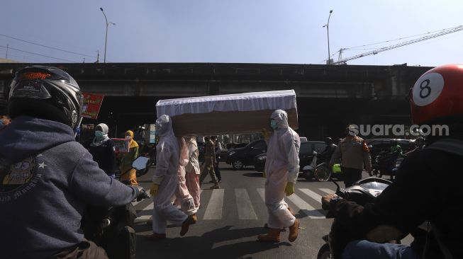 Petugas gabungan dari Kecamatan Cilandak dan Polsek Cilandak melakukan aksi sosialisasi bahaya COVID-19 dengan mengarak instalasi peti mati jenazah di kawasan Fatmawati, Jakarta, Jumat (28/8/2020). [Suara.com/Angga Budhiyanto]