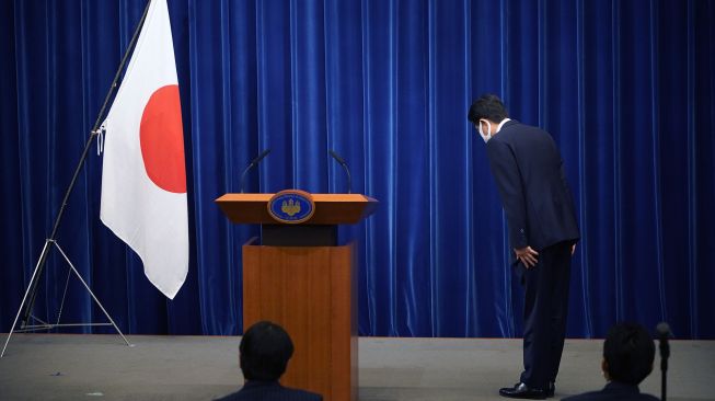 Perdana Menteri Jepang Shinzo Abe memberikan hormat kepada  bendera nasional saat memulai konfrensi pers di kediaman resmi Perdana Menteri, Tokyo, Jepang, Jumat (28/8).  [Franck ROBICHON / POOL / AFP]