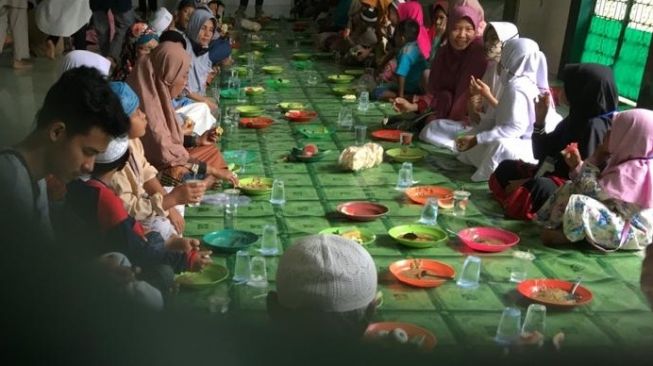 Suasana anak yatim menyantap Bubur Suro di Masjid Suro, Jalan Ki Gede Ing Suro, Kelurahan 30 Ilir, Kecamatan Ilir Barat II, Kota Palembang, Sabtu (29/8/2020). [Suara.com/Rio]