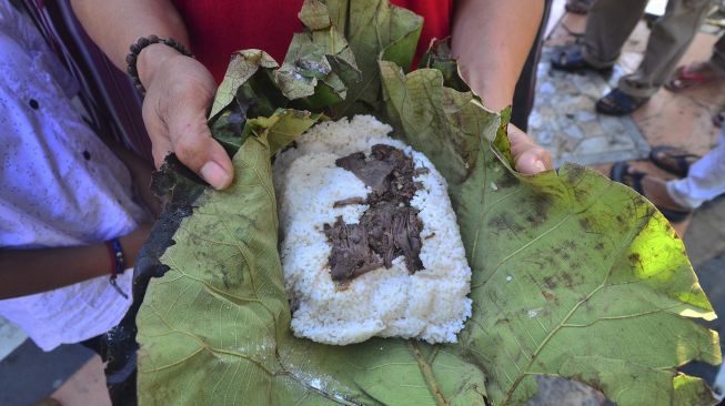 Warga menunjukkan nasi jangkrik saat Tradisi Membagi Nasi Jangkrik di kawasan Masjid Menara Kudus, Jawa Tengah, Sabtu (29/8/2020). [ANTARA FOTO/Yusuf Nugroho]