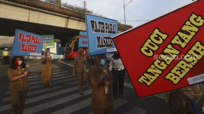 Sejumlah Aparatur Sipil Negara (ASN) membawa poster imbauan saat peresmian simbol peringatan COVID-19 di Simpang Lima Senen, Jakarta, Selasa (1/9/2020). [Suara.com/Angga Budhiyanto]