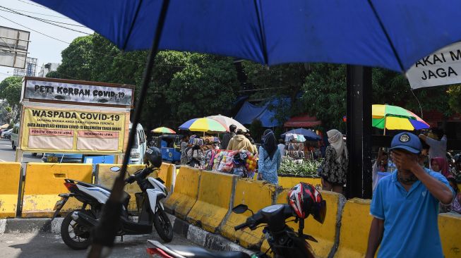 Warga melintasi replika peti mati dan papan himbauan waspada COVID-19 di kawasan Pasar Tanah Abang, Jakarta, Selasa (1/9/2020). [ANTARA FOTO/ Wahyu Putro