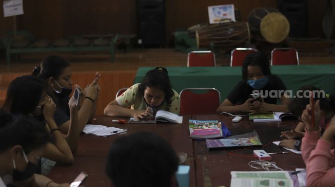 Sejumlah pelajar dari berbagai jenjang sekolah mengerjakan tugas dengan metode pembelajaran jarak jauh menggunakan fasilitas Wi-Fi gratis di balai warga RW 005 Kelurahan Kuningan Barat, Jakarta, Selasa (1/9/2020). [Suara.com/Angga Budhiyanto]