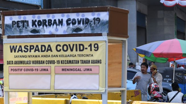 Warga tanpa mengenakan masker melintasi replika peti mati dan papan himbauan waspada COVID-19 di kawasan Pasar Tanah Abang, Jakarta, Selasa (1/9/2020).  [ANTARA FOTO/ Wahyu Putro]