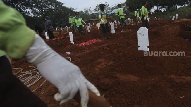 Petugas pemakaman mengali pusara untuk pemakaman penanganan jenazah pasien COVID-19 di TPU Pondok Ranggon, Jakarta, Rabu (2/9/2020). [Suara.com/Angga Budhiyanto]