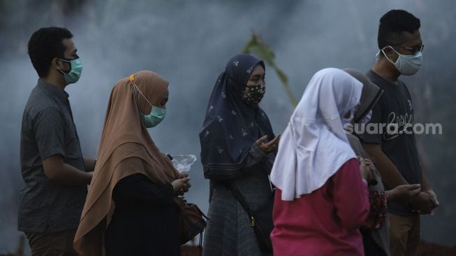 Keluarga jenazah pasien COVID-19 memanjatkan doa di TPU Pondok Ranggon, Jakarta, Rabu (2/9/2020). [Suara.com/Angga Budhiyanto]